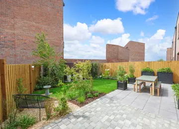 Beautifully landscaped garden with stylish furniture, green foliage, and a gorgeous grey patio.