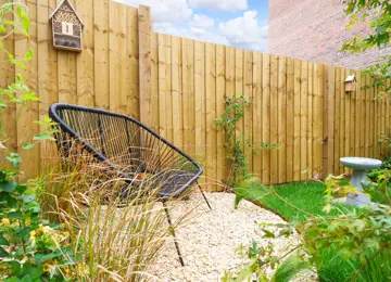 Outdoor seating area surrounded by luscious greenery and fence climbing plants.