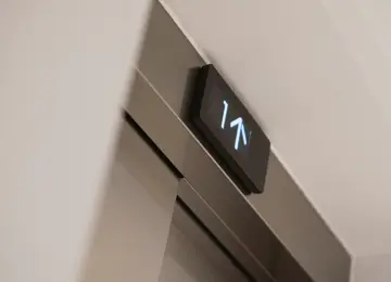 A close up of the apartment lift digital screen with arrows indicating going up a level.