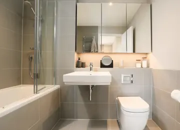 Family bathroom featuring an over shower bath, mirrored vanity unit and stylish extras.