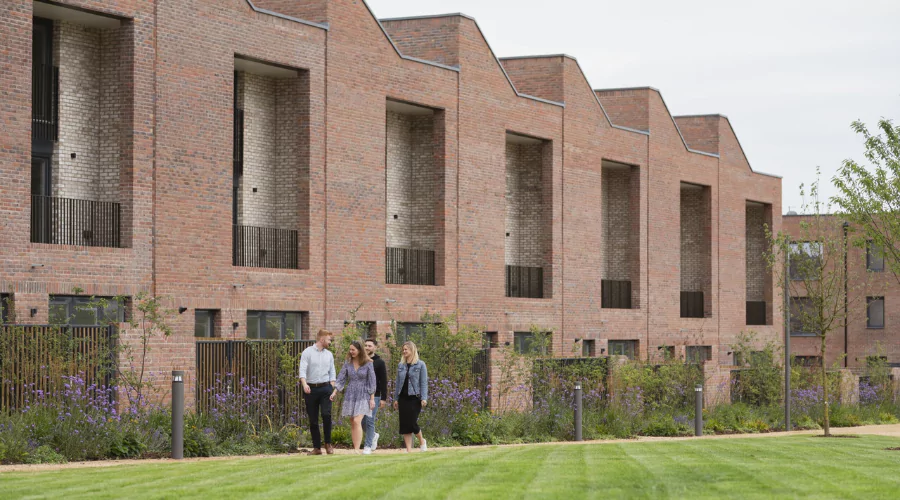 Four People walking along a footpath non the green space in Brabazon on a spring day in casual clothing.