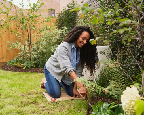 Young woman smiling as she digs in a flowerbed with a trowel