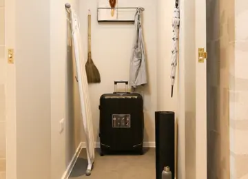 Apartment built-in storage cupboard hosting suitcases and a large ironing board.