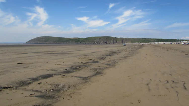 Golden sand beach on a sunny day with headland in the background