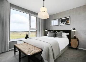 Principal bedroom flooded with natural light from expansive window, complemented by stylish furnishings.