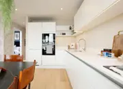 Long shot of glossy white kitchen counter tops featuring under cupboard lighting.
