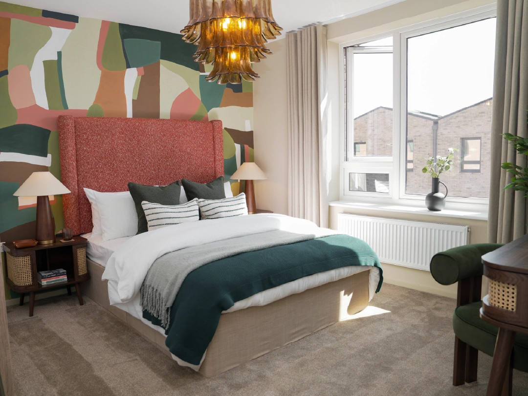 The Coanda Show Home Primary Bedroom A stylish primary bedroom at Brabazon, featuring a textured orange headboard, colourful mural, cozy bedding, and a large window with natural light.