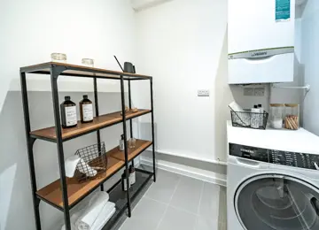 Utility room including the boiler and washing machine, featuring styled shelving.