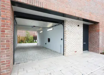 Pictured is a red brick car port including a electric car charger.