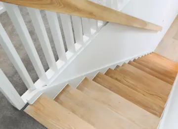 A stairway featuring engineered wood flooring and stair rail. 