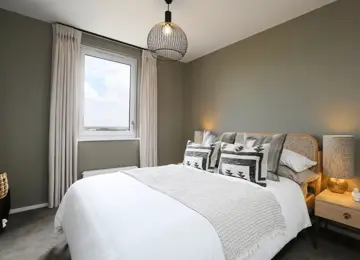 A styled sage green second bedroom featuring a double bed and stylish furnishings.