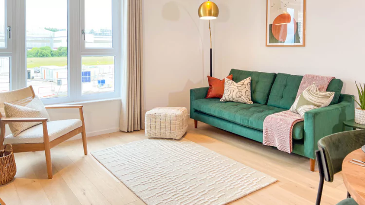 Bright and welcoming living-dining space with a green sofa, armchair and warm wood flooring