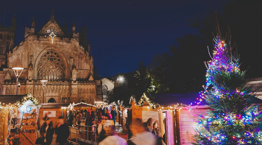 Exeter Christmas market featuring stalls, twinkly lights and a decorative Christmas tree.