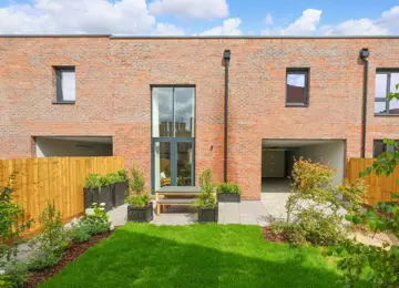 Stylish landscaped new build garden, styled with garden furniture, overflowing planters, featuring a spacious car port.