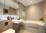 A wide angle of the family bathroom with added extras such as the large mirrored storage units and faux plants.