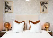 Burnt orange decor and matching bedside tables compliment this apartment primary bedroom.